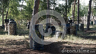 Paintball. Fenced area in the forest for the game of war. Old barrels and tires as shelters for players. Summer background. Sports Stock Photo