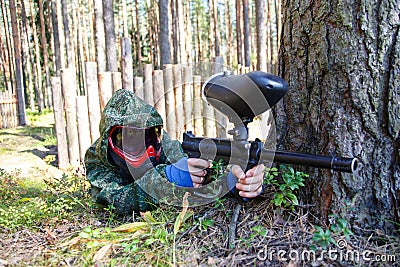 Paintball player behind pine tree aiming Stock Photo