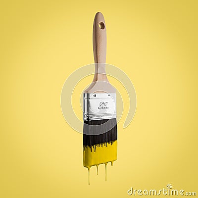 Paintbrush loaded with yellow color dripping off the bristle. Stock Photo