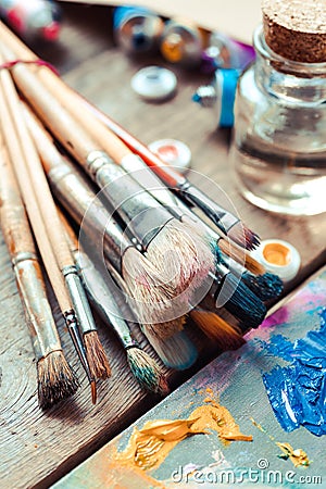 Paintbrushes closeup, artist palette and multicolor paint tubes. Stock Photo