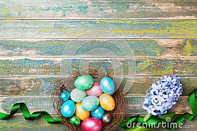 Painted colorful Easter eggs in nest with hyacinth flowers and ribbon top view. Festive background for spring holiday. Stock Photo