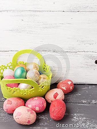 Painted Easter Eggs in decorated green basket on wooden table. Stock Photo