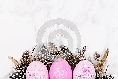 Painted Easter pink eggs with stylish feathers on a marble background. Holiday background. Stock Photo