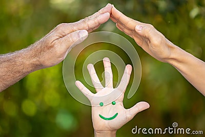 Painted smiley face on the palms against green background Stock Photo