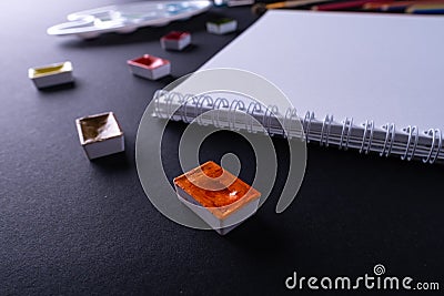 Painter artist work space paper pencil paintbrush paints at angle dark background Stock Photo