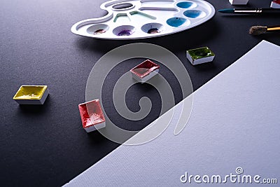 Painter artist work space paper pencil paintbrush paints at angle dark background Stock Photo