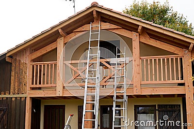 Painter ladder painting the wooden beams and railings of the house Stock Photo