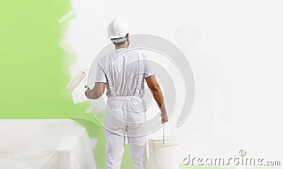 Painter man at work with a paint roller, wall painting green col Stock Photo