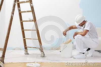 Painter man at work takes the color with paint roller from the b Stock Photo