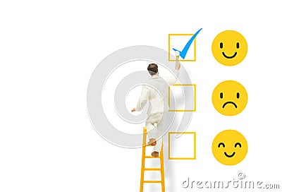 Painter standing on ladder and painting blue tick checkbox on face emotions in happiness symbol for best service ranking. Stock Photo