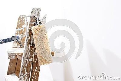 Painter wooden ladder with roller paint, leaning wall Stock Photo