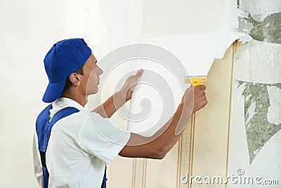 Painter worker peeling off wallpaper Stock Photo