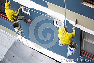 Painters hanging on roll, painting color on building wall Stock Photo