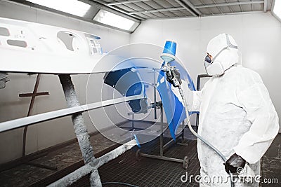 Painting the bumper of car in the paint room, spray gun with white paint. Stock Photo