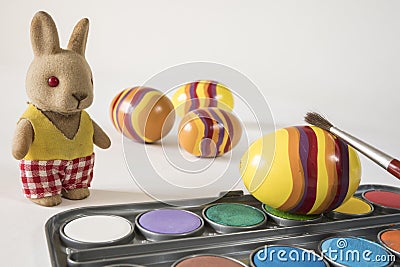 Painting Easter eggs with red brush. Easter bunny and yellow eggs. Stock Photo