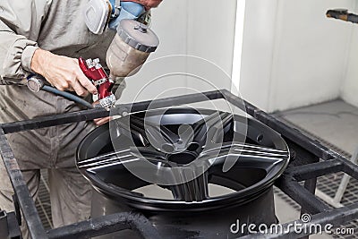 Painting the element body of the car - the aluminum alloy wheel with the help of aerograf in black color by the hand of painter Stock Photo