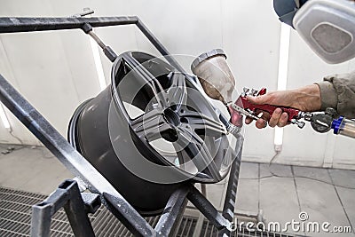 Painting the element body of the car - the aluminum alloy wheel with the help of aerograf in black color by the hand of painter Stock Photo