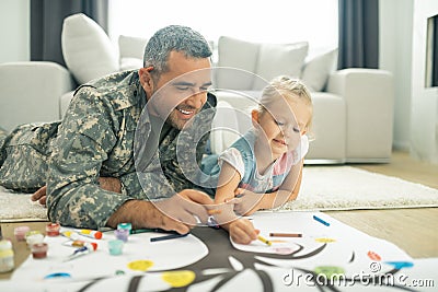 Military servant and his daughter painting family tree together Stock Photo