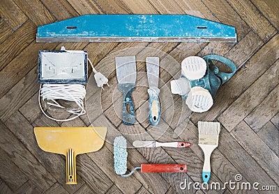 Painting tools and accessories on wooden floor, putty knifes, paint roller, brushes, respirator Stock Photo