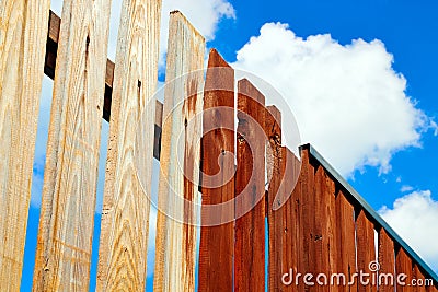 Painting wooden fence with brown paint. Blue sky background Stock Photo