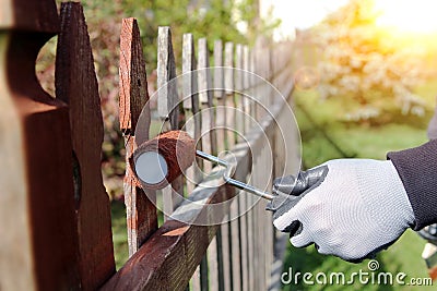 Painting wooden fence with brown paint outside Stock Photo