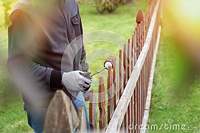 Painting wooden fence with brown paint outside Stock Photo