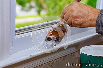 Painting a wooden with paintbrush while painting window trim Stock Photo