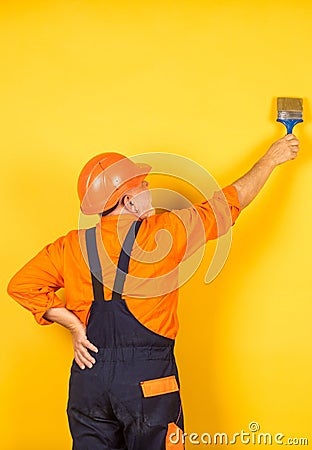 Painting yellow wall. painter in working uniform working indoor. man with painting brush. Professional Workman Hand Stock Photo