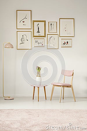 Paintings in golden frames, pink chair, table and lamp set on th Stock Photo