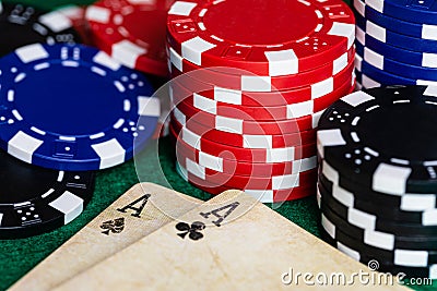 A pair of aces, Clubs and Spades, on well used vintage deck of playing cards, surrounded by Blue, Red and Black betting chips on a Stock Photo