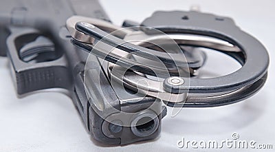 A pair of black and silver handcuffs on top of a black pistol Stock Photo