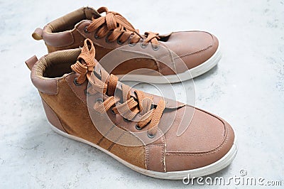 A pair of brown unisex high cut sneaker shoes laid out on a cement floor Stock Photo