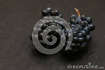 Pair of bunches of dark ripe grapes on wooden black table Stock Photo