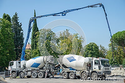 Pair of Cement trucks with extended hydraulic systems pouring cement Stock Photo