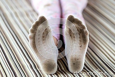 Pair of child feet in dirty stained white socks. Kid soiled socks while playing outdoors. Children clothes bleaching and Stock Photo