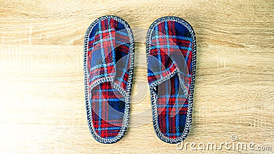 A pair of colorful comfortable, cushioned, checkered disposable slippers are on the wooden floor. Close-up Stock Photo
