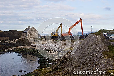 A pair of cranes used to dredge the small harbor at Ballintoy on the North Antrim Coast of Northern Ireland on a calm spring day. Editorial Stock Photo