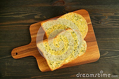 Pair of Delectable Homemade Garlic Butter Whole Wheat Toasts on Wooden Breadboard Stock Photo
