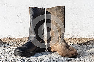 A pair of different boots outdoor. Contrast old and new, clean and dirty shoes Stock Photo