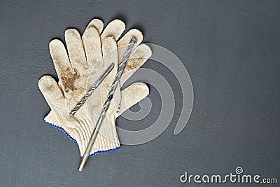 Pair of dirty textile protective gloves for repair or other hard works near old messy drills Stock Photo