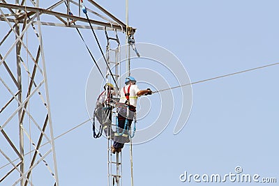 Workers over a high tension tower making reparations. Editorial Stock Photo