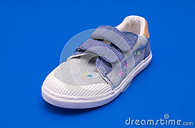 Pair of fashion denim baby shoes for the toddlers feet. Kids sneakers isolated on blue background. Stock Photo