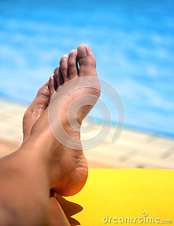Pair of feminine feet resting on a sun lounger by the pool Stock Photo