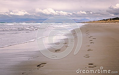 Pair of foot prints on a deserted beach on cloudy evening Stock Photo