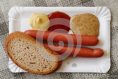Pair of frankfurter sausages with a slice of bread on paper plat Stock Photo