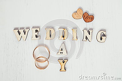 Pair gold rings with two wooden hearts and inscription wedding day on white background Stock Photo