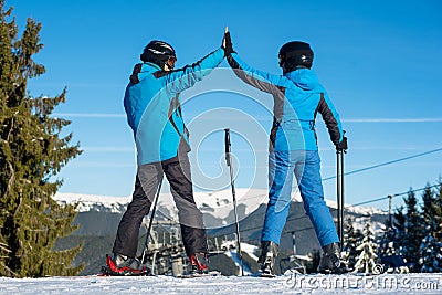 Pair holding hands standing with skis on mountain top Stock Photo
