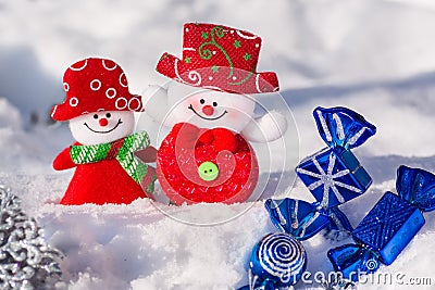 A pair of merry snowmen in the snow with Christmas toys with blue candies and a silvery snowflake. Merry Christmas Stock Photo