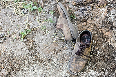Pair of old dirty used shoes. Abandoned discarded boots laying in dust on ground. Poverty or beggary concept. Copyspace Stock Photo
