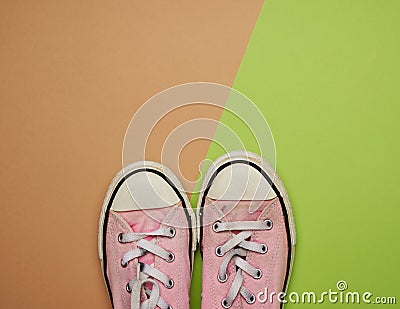 Pair of old worn pink sneakers with white laces on a green background Stock Photo
